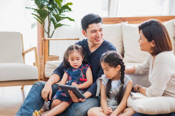 happy asian family using tablet, laptop for playing game watching movies, relaxing at home for lifestyle concept - father digital tablet asian ethnicity daughter imagens e fotografias de stock