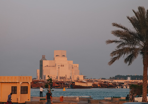21st October 2019,Doha,Qatar: Local people walking by the sea road during sunset, the museum of islam art can be seen in the background.