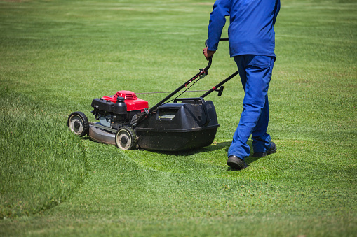 African man cutting grass with a lawnmower,