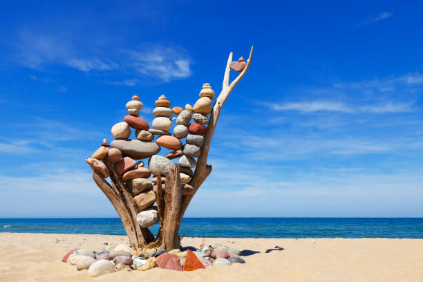 pile de pierres équilibrées multicolores sur un vieux chicots en bois, sur un ciel bleu et fond de mer - perfection nature balance stone photos et images de collection
