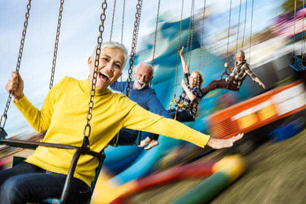 istock Carefree seniors having fun on chain swing ride at amusement park. 1185367389