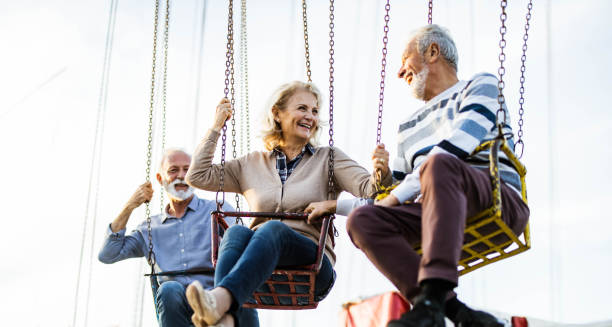 istock Panoramic view of happy senior couple talking on chain swing ride. 1185367646