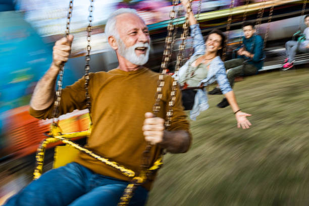 istock Happy senior man having fun while riding on chain swing at amusement park. 1185367806
