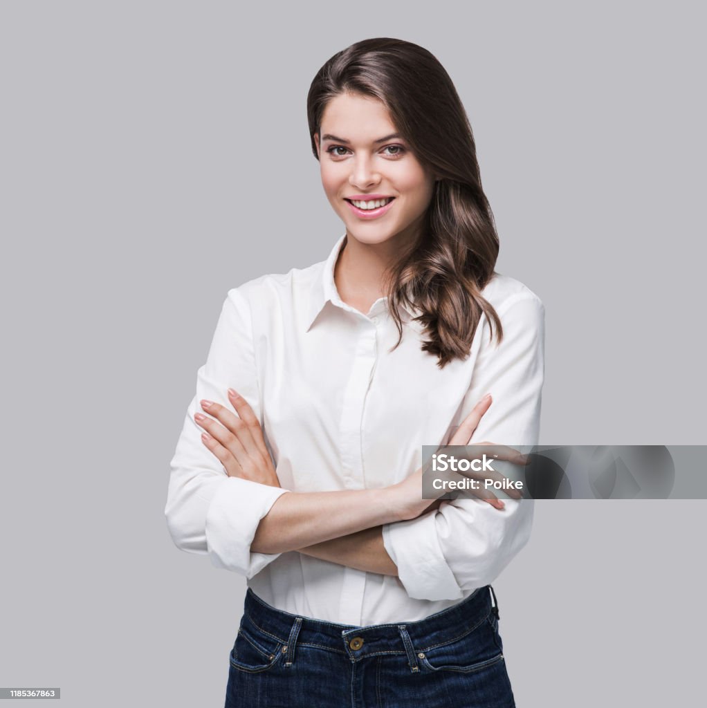 Smiling business woman portrait Beautiful girl with crossed arms looking at camera. Studio shot. Isolated on gray background Women Stock Photo