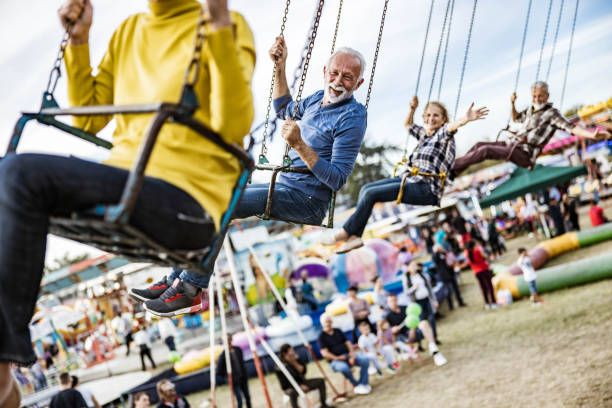 istock Happy senior friends having fun while riding on chain swing at amusement park. 1185368107