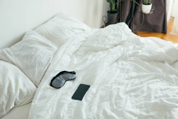 istock sleeping mask with phone at bed with white sheets sunny morning bedroom 1185370377