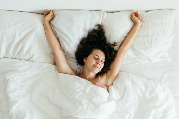 istock young pretty woman in bed with white sheets bright light copy space 1185370392