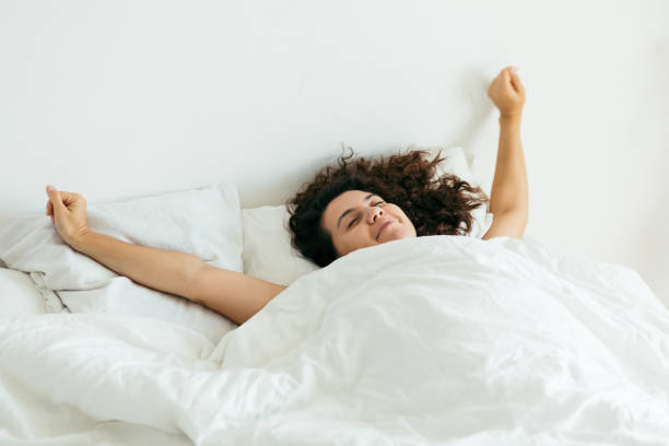 istock young pretty woman in bed with white sheets bright light copy space 1185370397