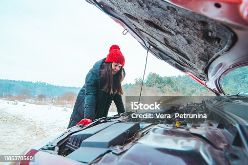 istock woman looking at car engine road assistance concept winter season 1185370560