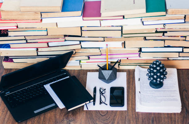 istock Open textbook, notebook, smartphone, laptop computer, stack of books education back to school background, paperweight, documents, glasses and pencils in holder with copy space for text 1185370602