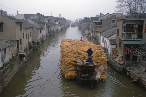 China (exact location unfortunately not known), 1985. Rice transport barge to a water channel. Furthermore: boat crew and buildings.