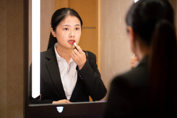 istock Young Asian woman applying lipstick 1185372887
