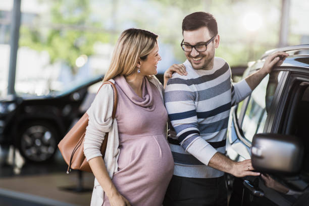 szczęśliwa para w ciąży rozmawia podczas zakupu nowego samochodu w salonie. - common family new togetherness zdjęcia i obrazy z banku zdjęć
