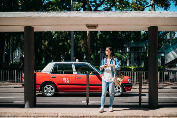 Woman waiting on tram station with a red taxi on background stock photo