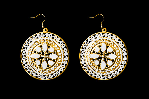 Pair of large gold ethnic earrings isolated over black