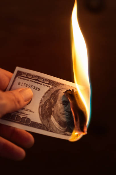 istock Hand holds burning American hundred-dollar banknote 1185377672