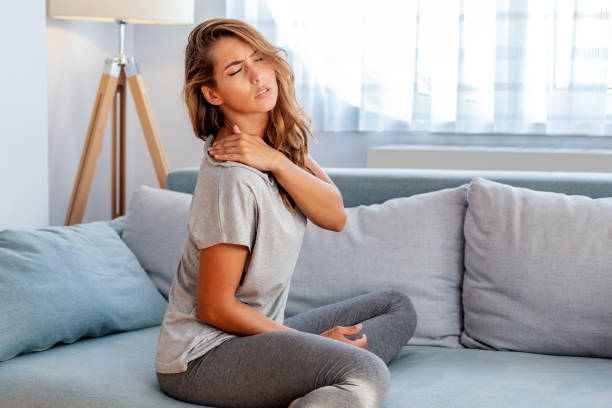 dolore alla spalla. dolore alla parte superiore del braccio, persone con problema corpo-muscoli, concetto di assistenza sanitaria e medicina. donna attraente seduta sul letto e con una spalla dolorosa con un'altra mano. - shoulder bone foto e immagini stock