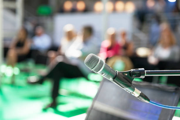 istock Microphone in focus against blurred people at business presentation 1185383801