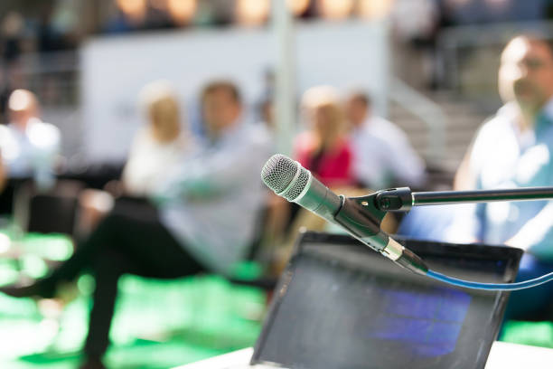 istock Microphone in focus against blurred people at business presentation 1185385281