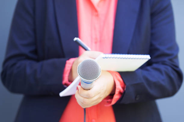 istock Reporter at news conference or media event, writing notes, holding microphone 1185386708