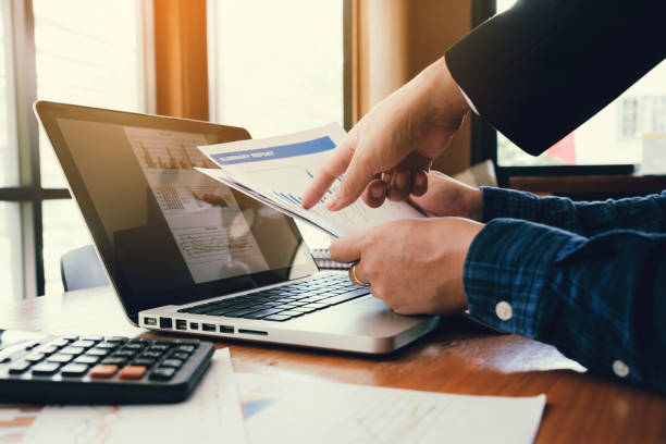 istock young business man hand holding graph chart and partner pointing graph chart for analyze the company's sales plan in the office. 1185386947