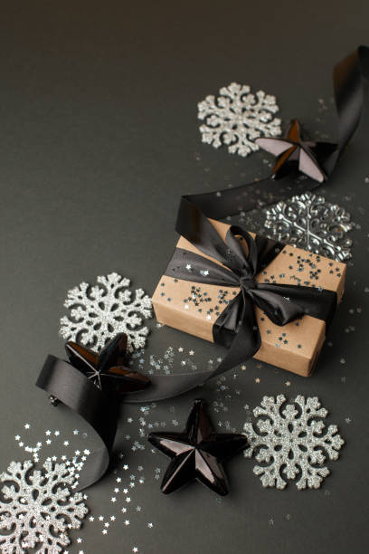 istock Christmas minimalistic and simple composition in mat black and silver color. Christmas gift, toys decorations on black background. Flat lay, top view with copy space, sale, discount 1185387151