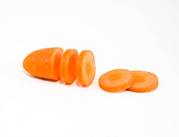 nahaufnahme karotten in stücke geschnitten mit reflektierenden orangen schatten auf weißem hintergrund - carrot isolated white carotene stock-fotos und bilder