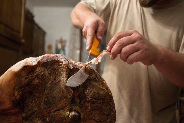 Home cutting of home made prosciutto: a man with the knife stock photo