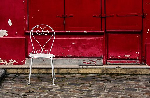 Old white chair in front of a red wall