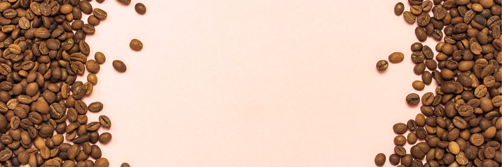 Coffee grains on the sides and free space in the center on a gently pink background. Flat lay, top view. Banner.