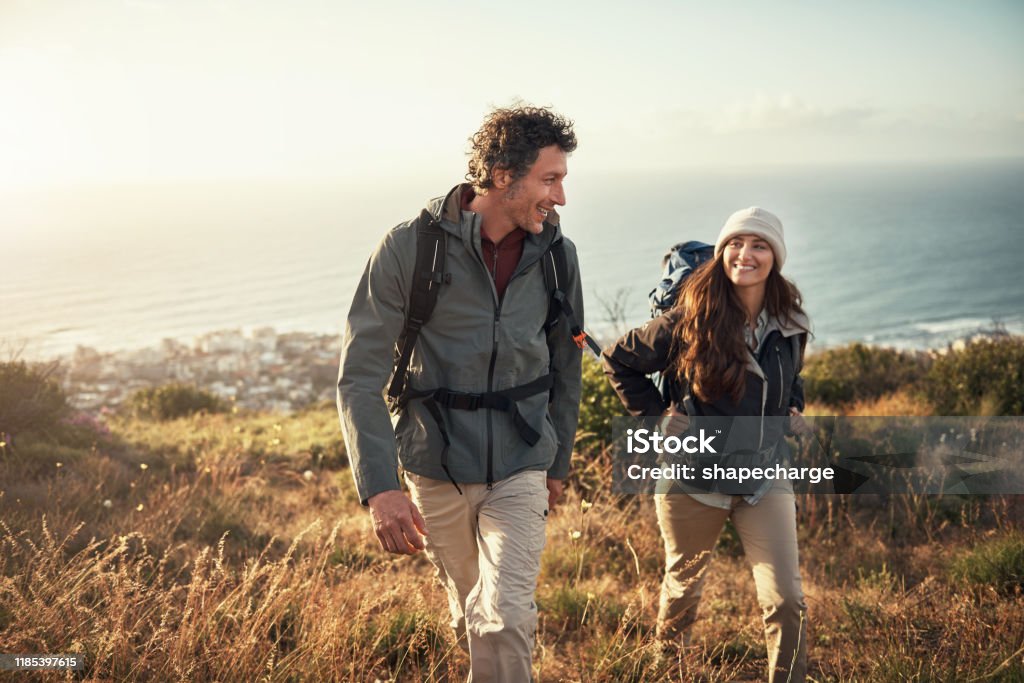 Taking their date to the top of the mountain Shot of a couple going for a hike up the mountain Hiking Stock Photo