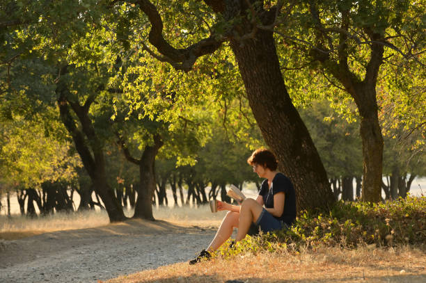 istock Woman reading a book in autumn forest 1185399401