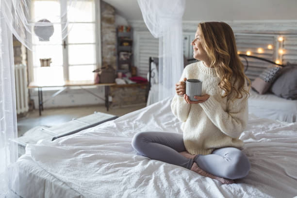 istock Beautiful young woman drinking coffee at home 1185402897