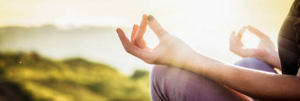 woman doing yoga in beautiful nature background at sunset or sunrise, focus on hand - mindfulness and mental health and hygiene background stock photo