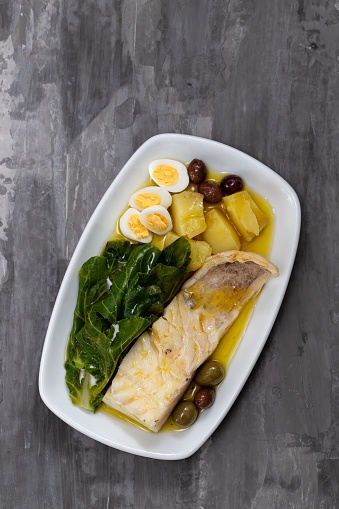 cod fish with cabbage, potato and olives on dish