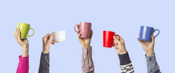 istock Many different hands holding multi colored cups of coffee on a blue background. Female and male hands. Concept of a friendly team, a coffee break, meeting friends, morning in the team. Banner 1185407676