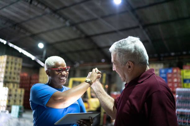 istock Partners celebrating good news and using digital tablet at warehouse 1185410025