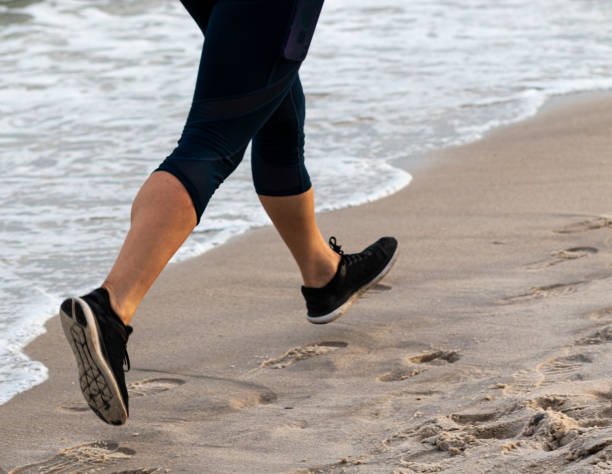 istock Runners legs as she runs along the water on the beach 1185410504