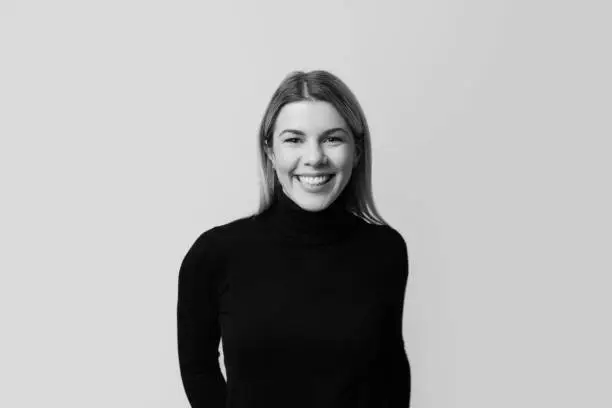 Black and white portrait of a smiling woman on grey background.