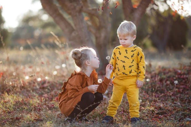 szczęśliwe romantyczne dzieci chłopiec i dziewczyna bawią się razem w jesiennym parku w ciepły wieczór o zachodzie słońca - couple autumn fashion male beauty zdjęcia i obrazy z banku zdjęć