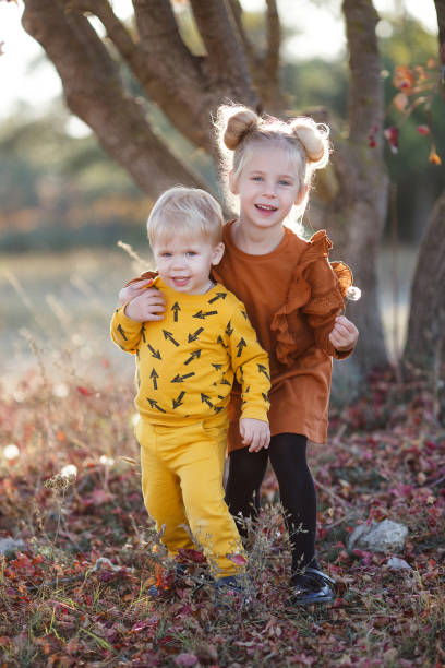 szczęśliwe romantyczne dzieci chłopiec i dziewczyna bawią się razem w jesiennym parku w ciepły wieczór o zachodzie słońca - couple autumn fashion male beauty zdjęcia i obrazy z banku zdjęć