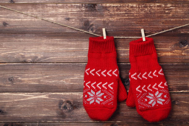 istock Knitted mittens hanging on brown wooden background 1185416596