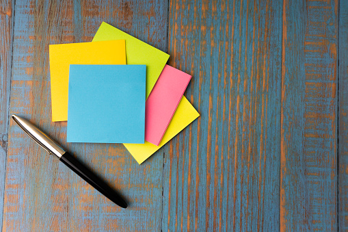 Minimalist flat lay composition of fountain pen and sticky notes on the wooden table top view. Copy space concept