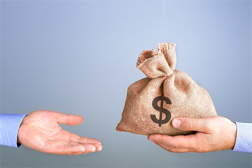El hombre sostiene, da una bolsa de dinero en la mano como un bono. Hombre de negocios sosteniendo bolsa de dinero en la mano ofreciendo soborno con espacio de copia. photo