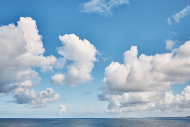 Sparse Seascape, Cloud in blue sky over calm sea, Newquay, Cornwall on a bright Autumn day.