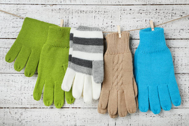 istock Knitted mittens hanging on white wooden background 1185418258