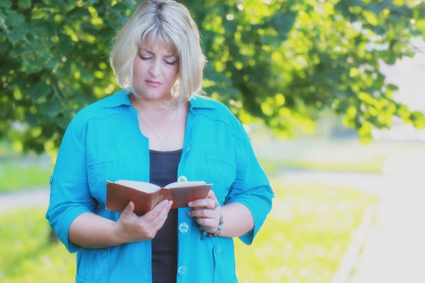 istock woman in the park green tree with book 1185418347