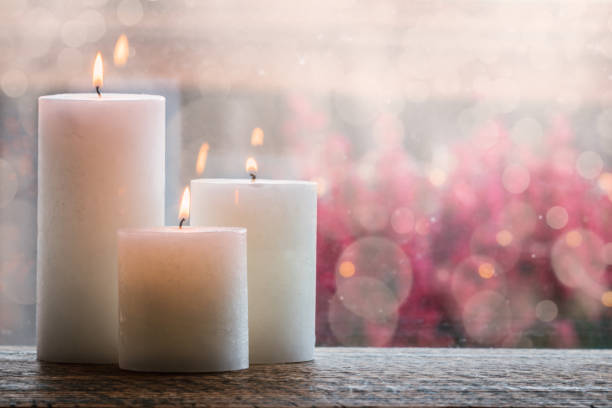 White burning candles with bokeh. White burning candles on wooden table with bokeh and blurry background. candlemas stock pictures, royalty-free photos & images