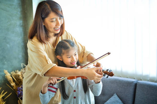 istock Asian kid learning and practicing to play violin at home 1185419438