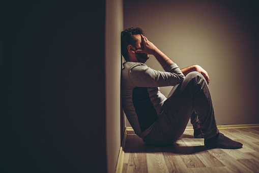 Young depressed man sitting on floor.